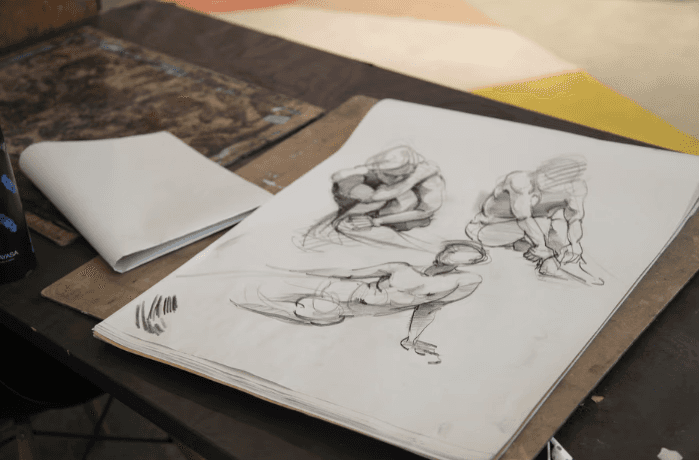 Sketchbook of dynamic figure gesture drawings lying open on a studio table
