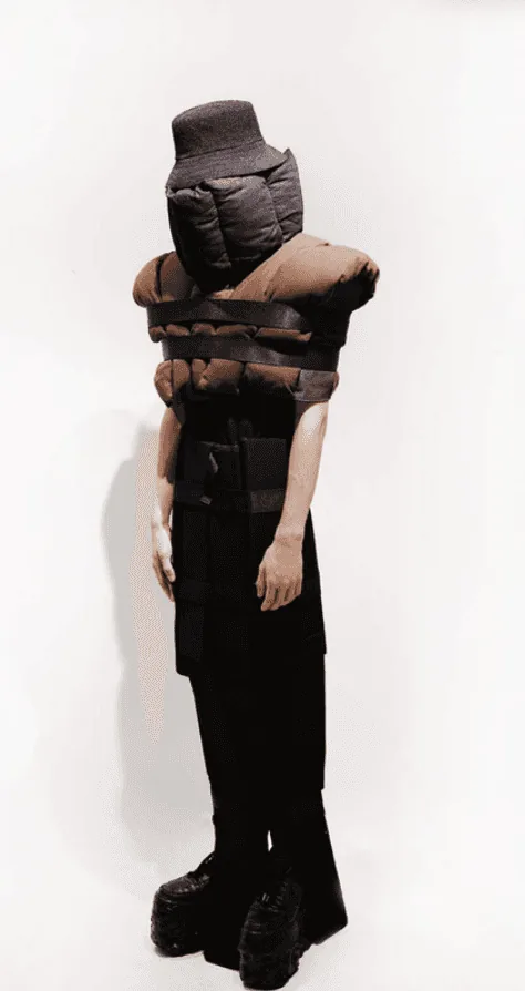 Avant-garde student fashion design: padded brown bodice with straps and face-covering hood on a model