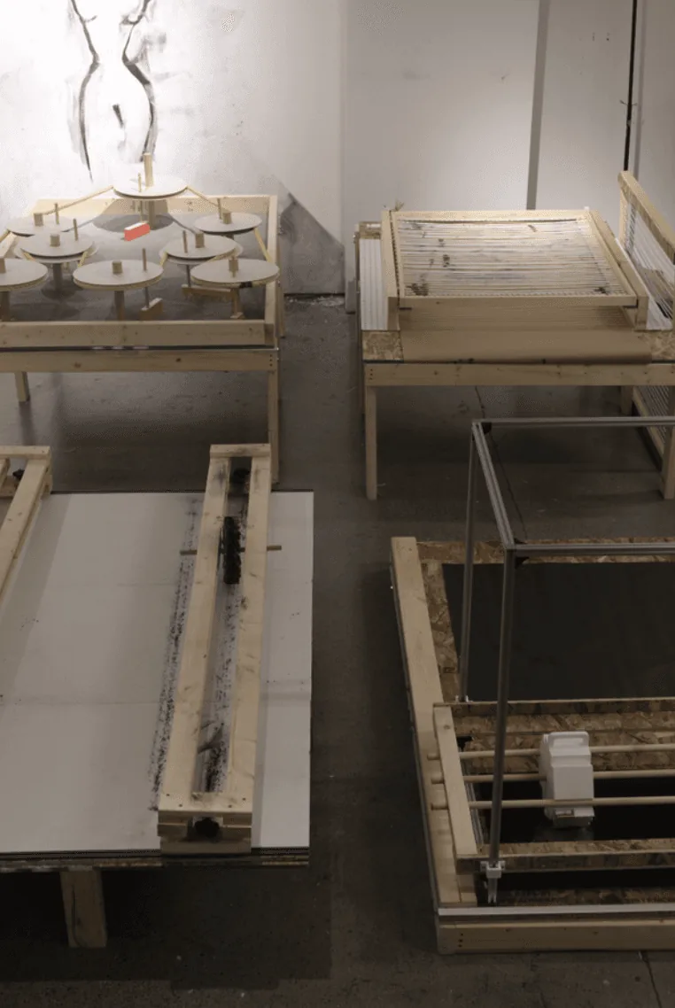 Studio installation of wooden frame tables and lightbox panels in an exhibition space